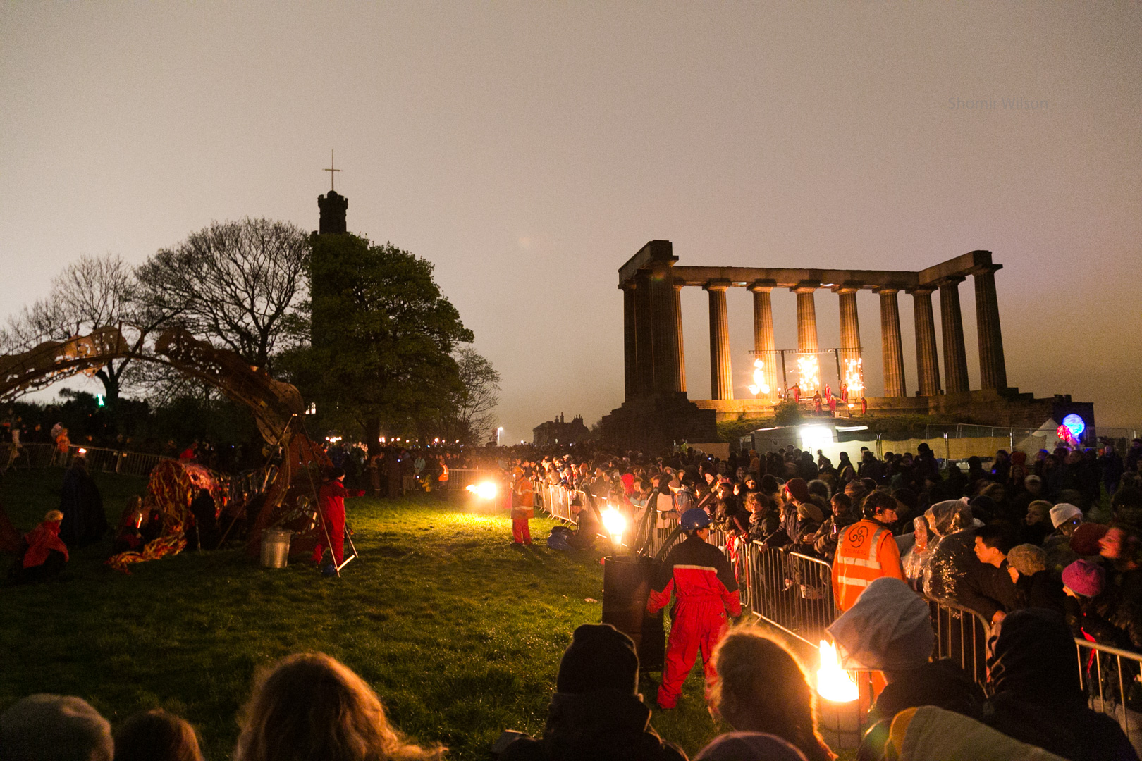 A crowd and event performers with fire at dusk