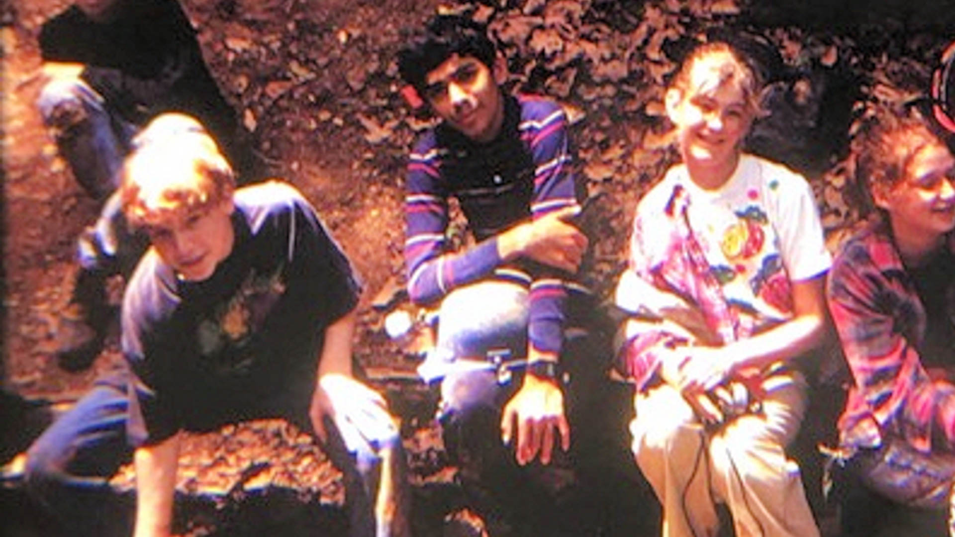 Me as a young teenager, wearing a striped shirt and with a gray hardhat on my lap, flanked by two other kids