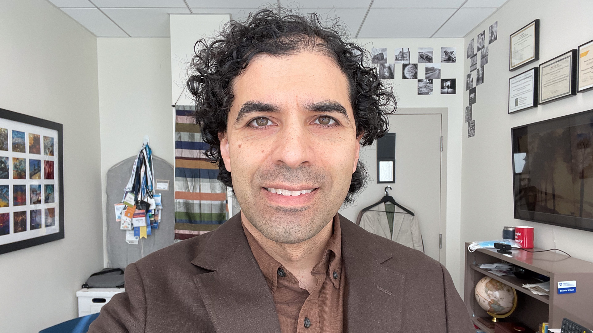 Me in my office at Penn State, with my photography on the wall and a globe on a shelf