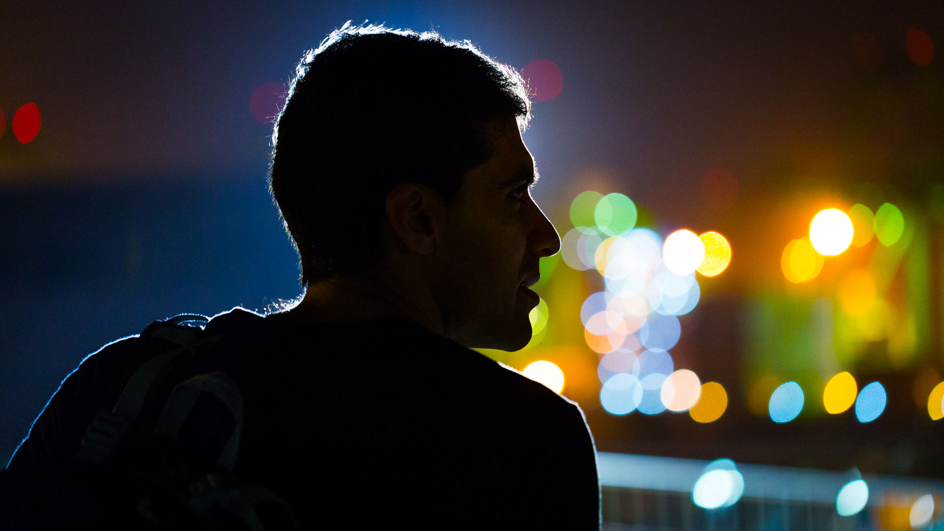 Dark silhouette of me from the shoulders up, with bokeh'd bright lights to my right