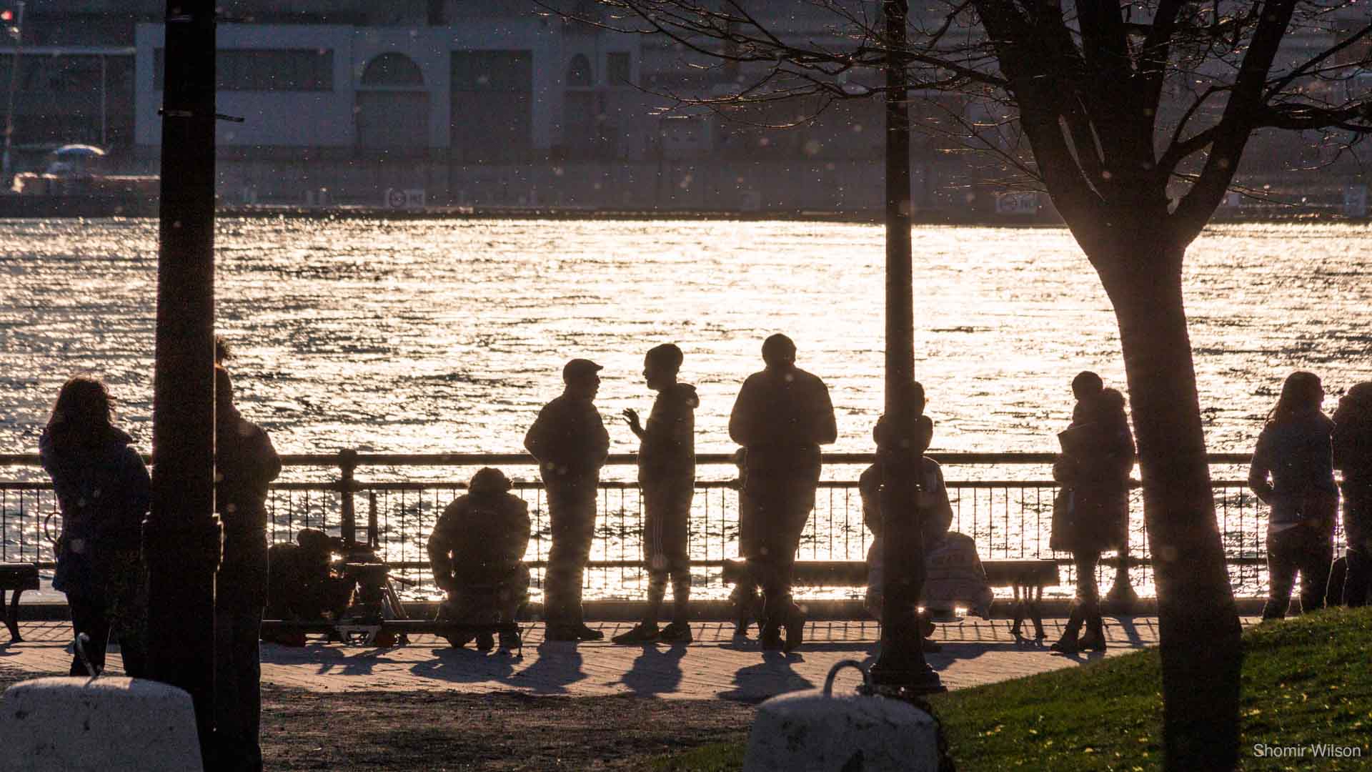 Silhouettes of people against a river lit brightly by the sun