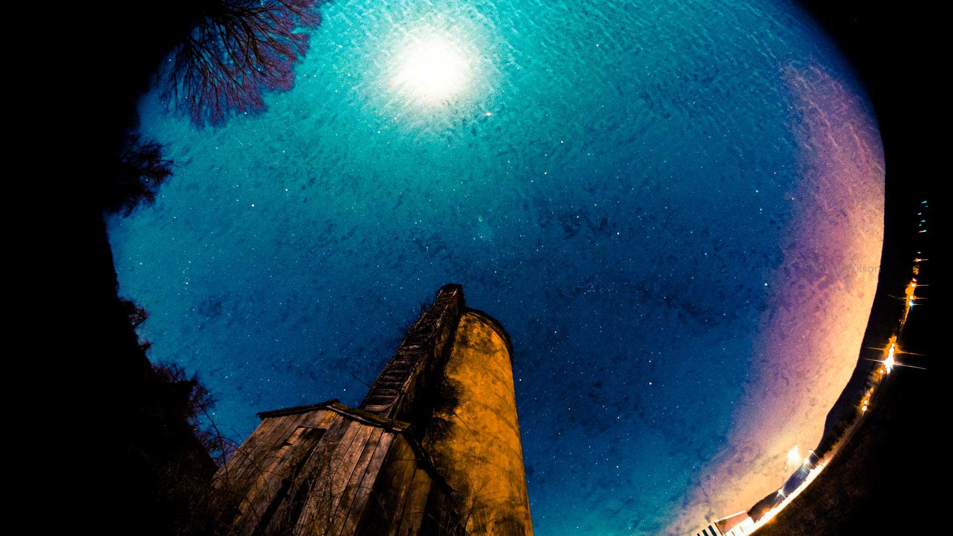 Fisheye view facing upward next a silo with the night sky, overlain with gentle ripples