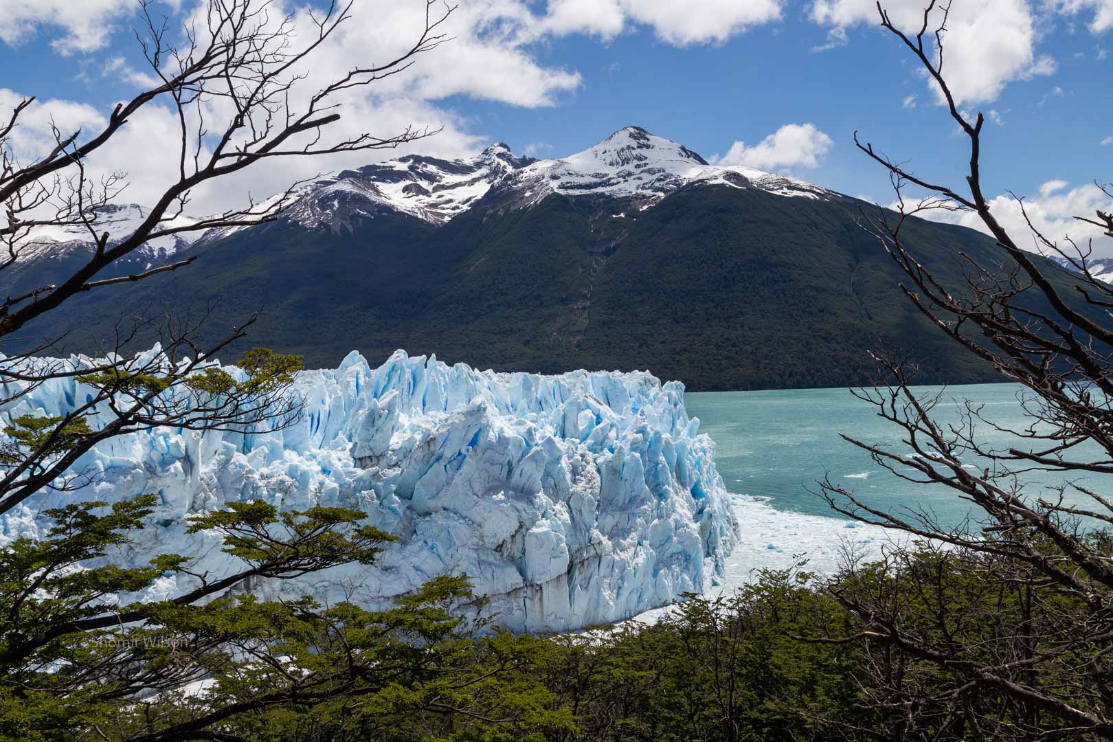 below, a blue glacier; above, snowcapped mountains