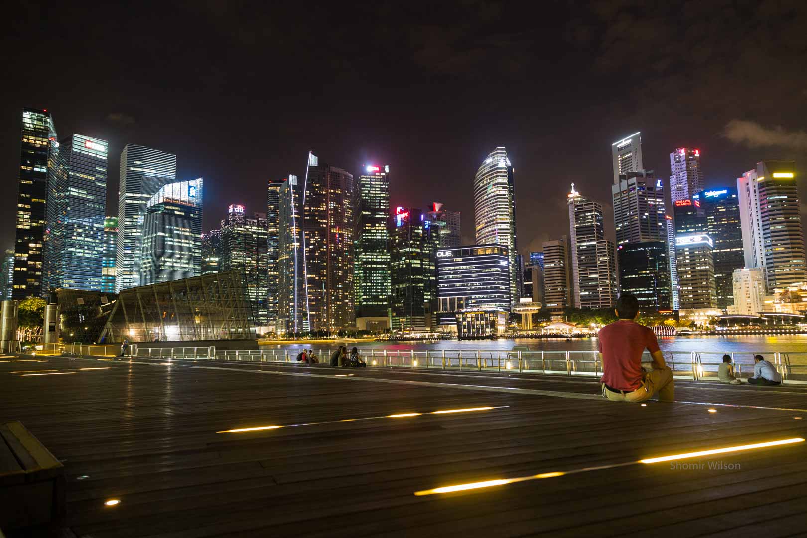 tall buildings of a large city, lit up at night, from the perspective of a nearby plaza