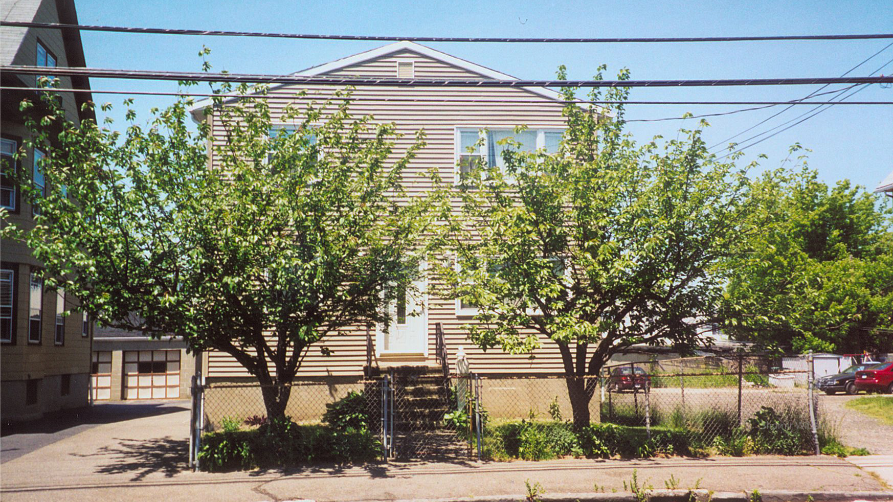 Two-story house with trees and sidewalk in front