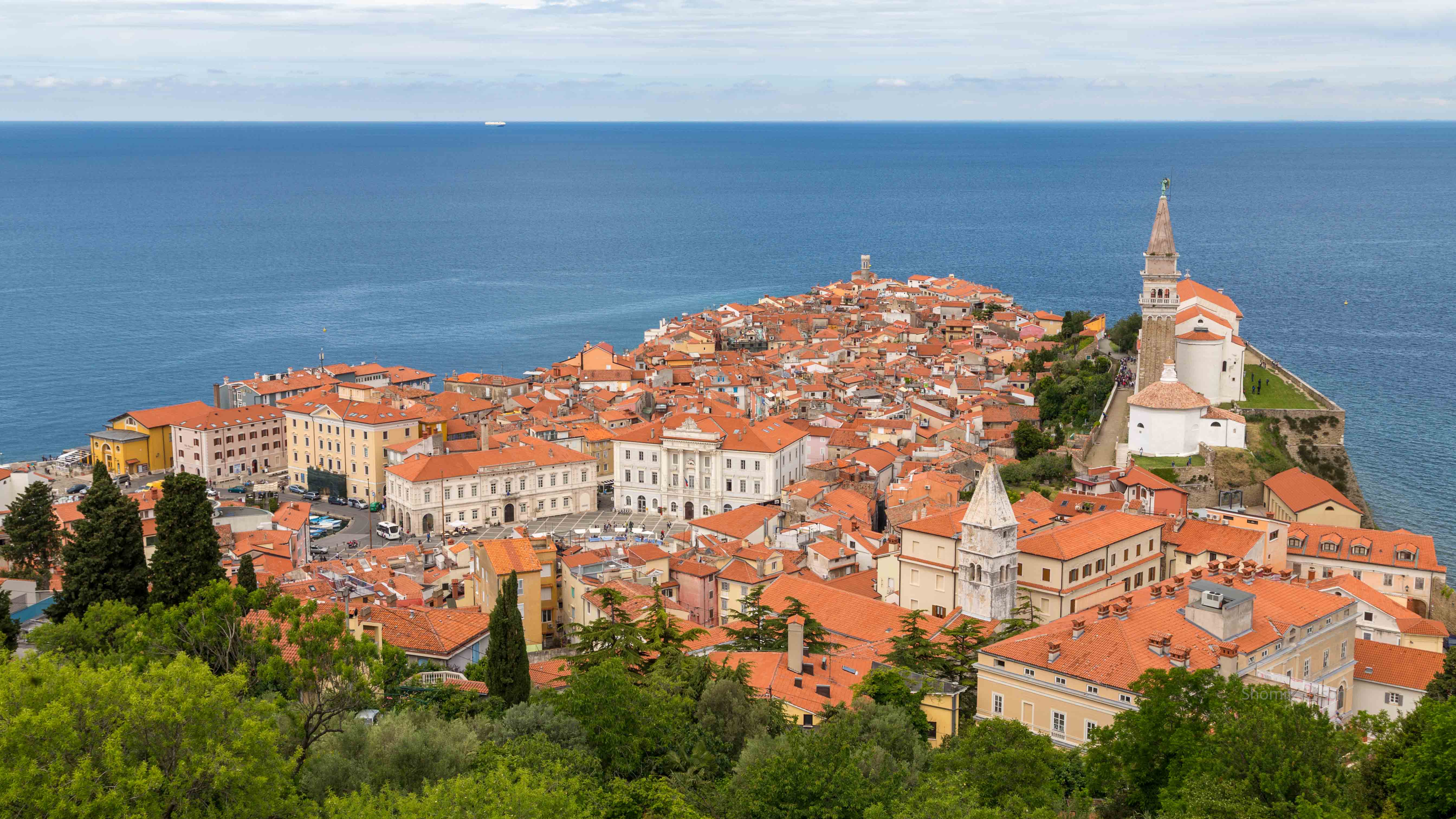 European town with many orange roofs on a peninsula into water