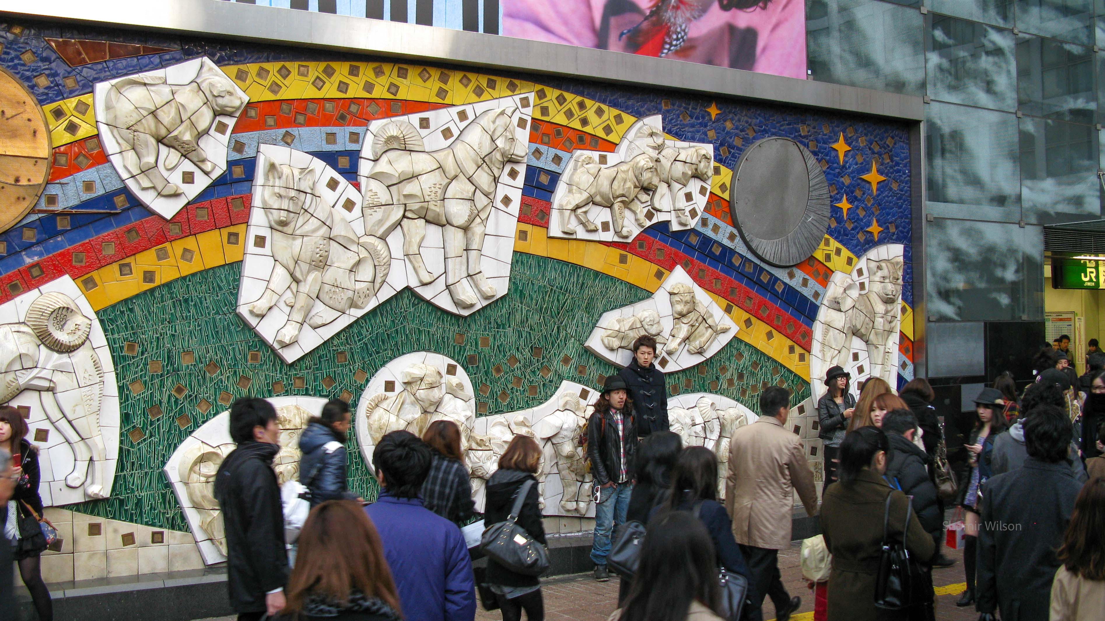 Large mural with many figures of the same dog, with many people walking by