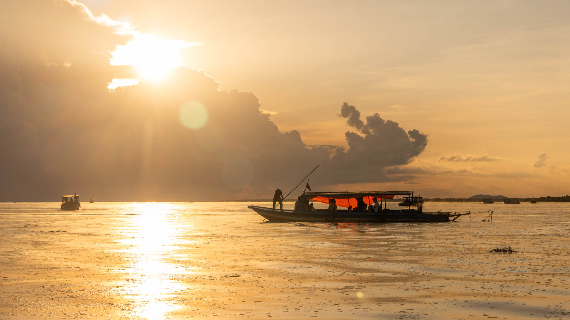 boats in front of an orange sunset on a large body of water